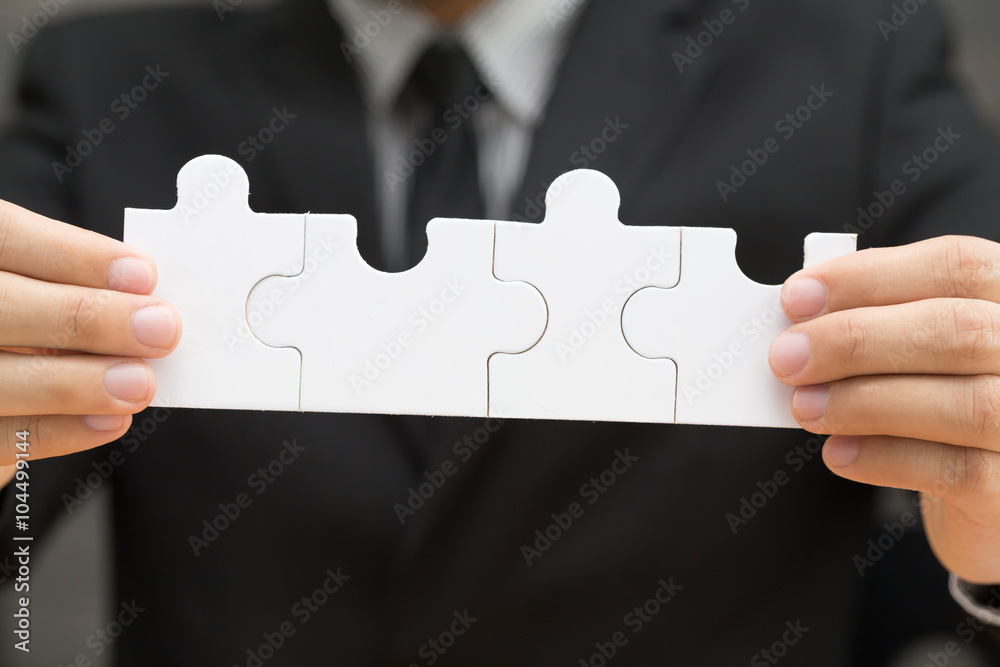Businessman holding four jigsaw to connect Businessman holding four jigsaw to connect