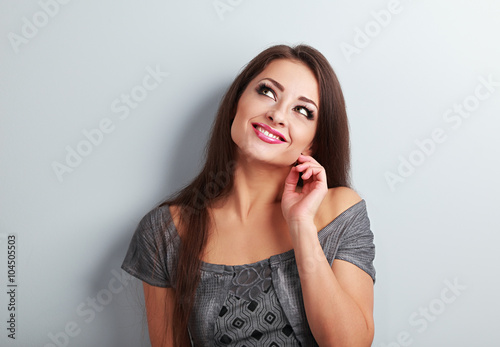 Happy thinking makeup woman looking up with hand near face on bl
