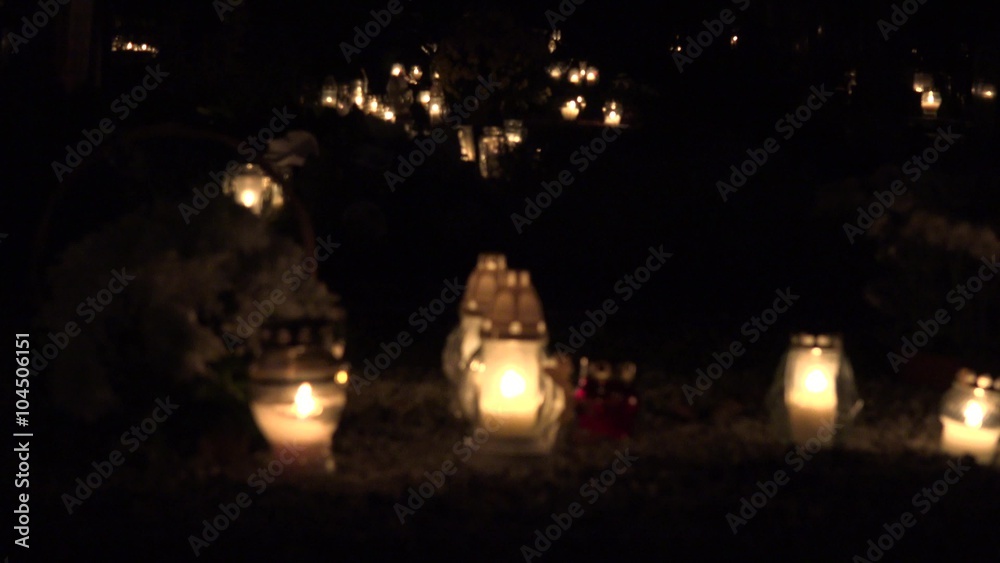 Flaming candles light on in graveyard on All saints day at night. Focus change shot. 4K
