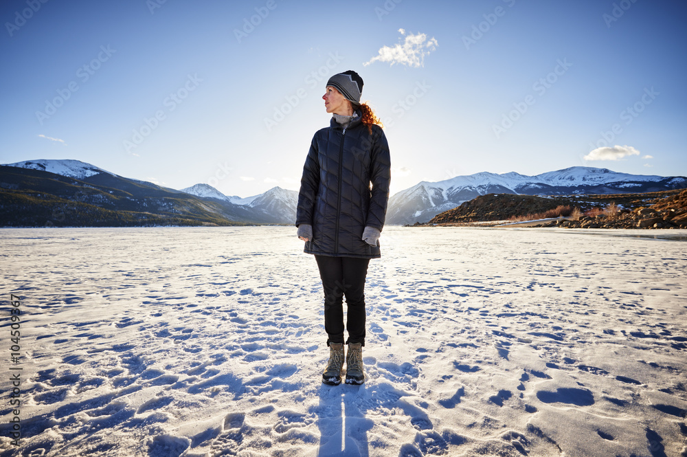 young woman standing on a frozen mountain lake