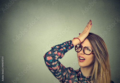 silly young woman, slapping hand on head having duh moment. Regrets wrong doing