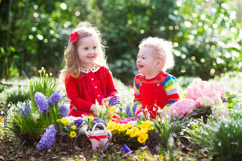 Kids planting flowers in blooming garden