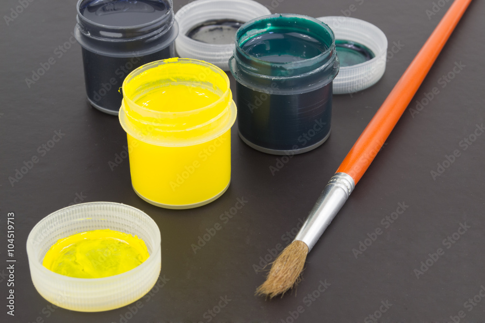 cans of paint and a brush on a black background
