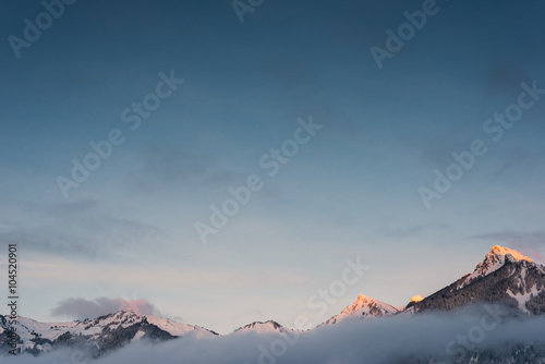 snowy orange peaks of mountain chain in winter with fog