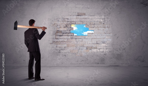 Business man hitting brick wall with hammer