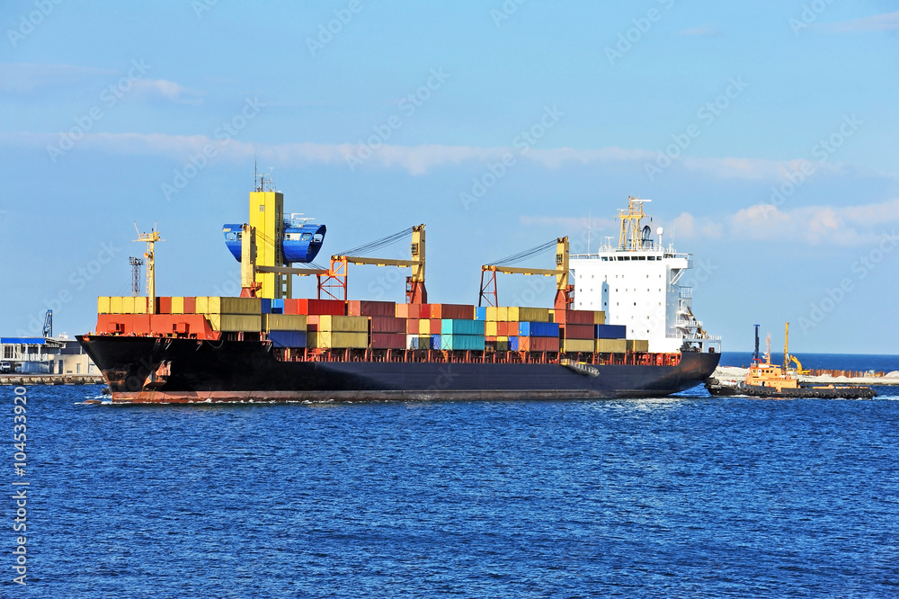 Tugboat assisting container cargo ship