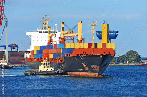 Tugboat assisting container cargo ship