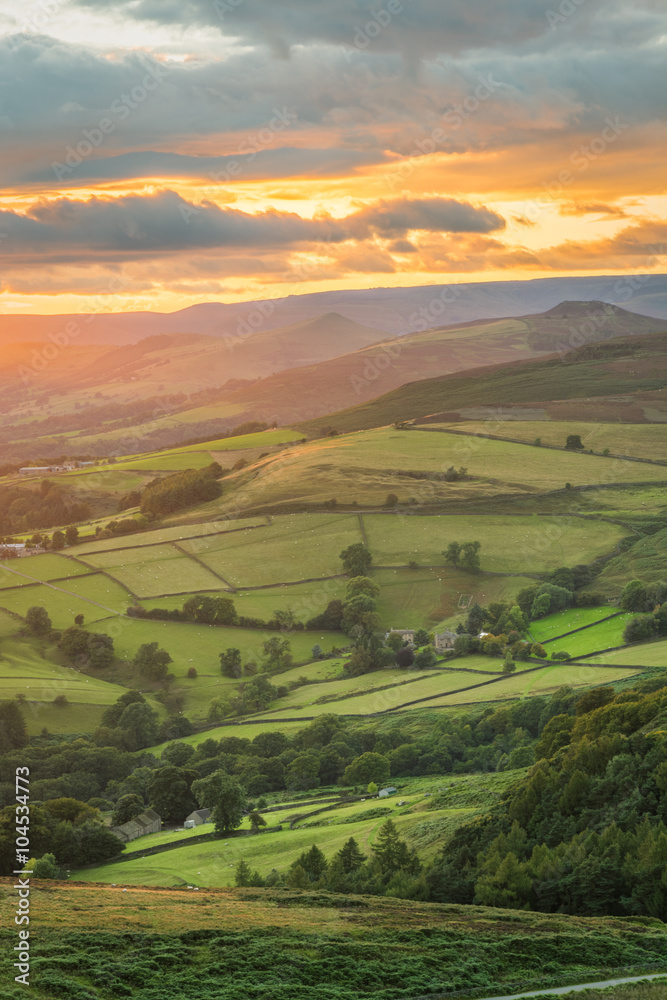 Beautiful golden glowing sunlight shining down on British green countryside at Stanage Edge in the Peak District, UK.