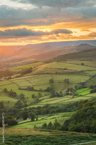 Beautiful golden glowing sunlight shining down on British green countryside at Stanage Edge in the Peak District, UK.