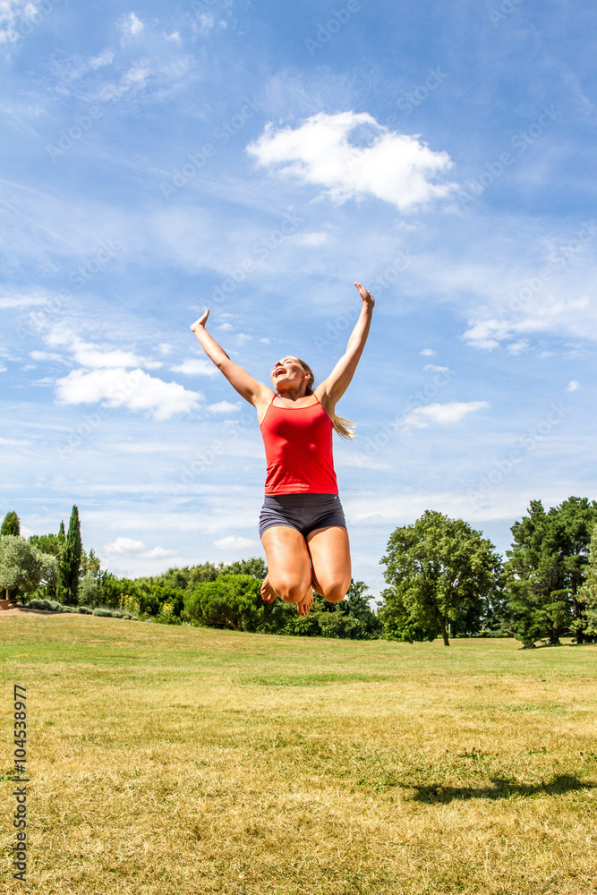 vitality and happiness outdoors - happy young blond woman jumping high to reach the sky to achieve success in green park, sunny summertime vitality and happiness outdoors - happy young blond woman jumping high to reach the sky to achieve success in green park, sunny summertime