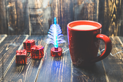 a red cup of coffee with red Christmas ornament on the dark wood