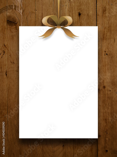 Close-up of one hanged paper sheet frame with brown ribbon on brown wooden background