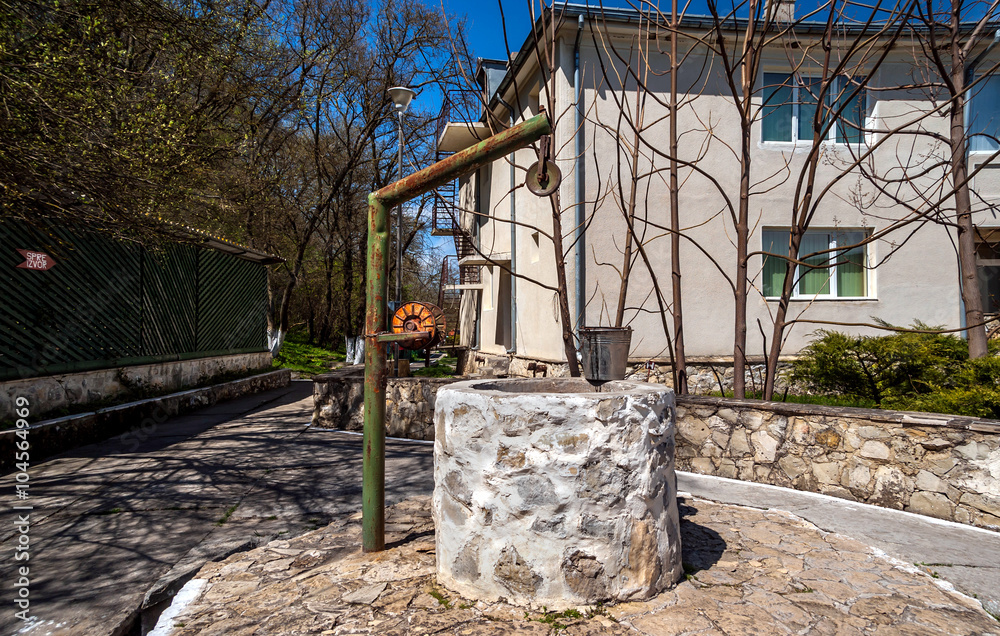 Fototapeta premium Traditional Romanian fountain with water bucket at St Andrew's Monastery ,Romania