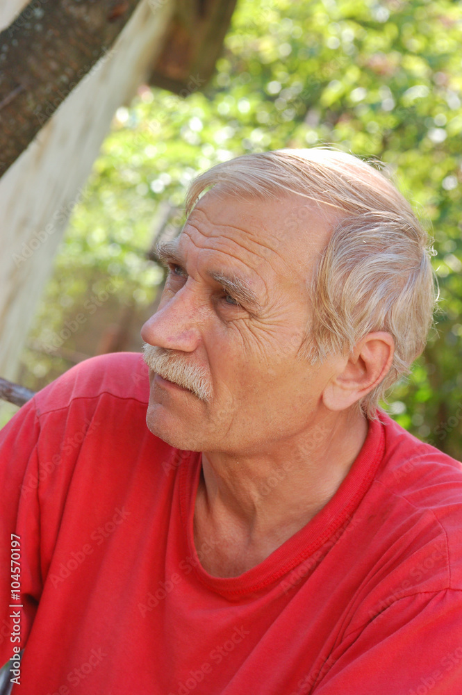 Portrait of a senior man in red. Thinking about something.