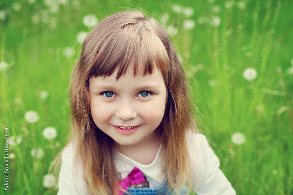 portrait of cute little girl with beautiful smile and blue eyes sitting on the flower meadow, happy childhood concept, child having fun, toned image portrait of cute little girl with beautiful smile and blue eyes sitting on the flower meadow, happy childhood concept, child having fun, toned image