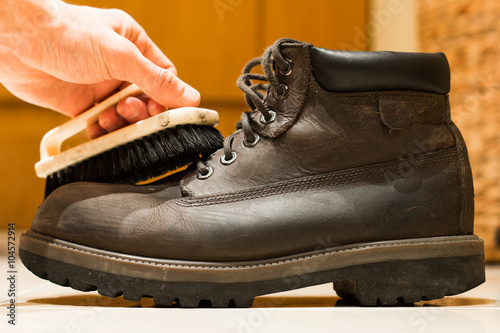 man cleans gray leather shoes closeup.