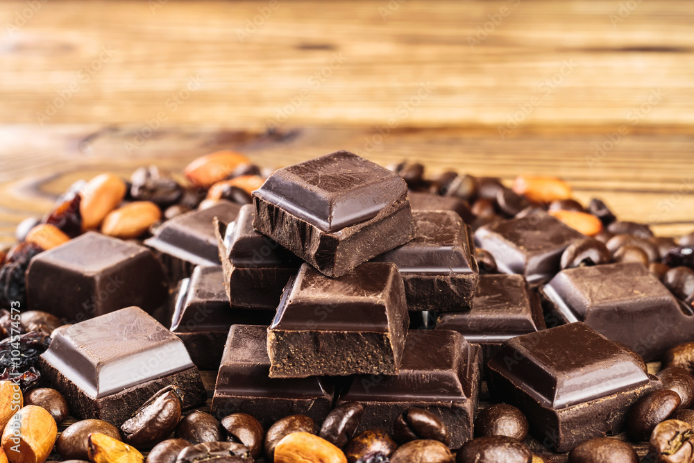Dark chocolate cubes, coffee beans, peanuts and raisins on wooden table, close-up Dark chocolate cubes, coffee beans, peanuts and raisins on wooden table, close-up