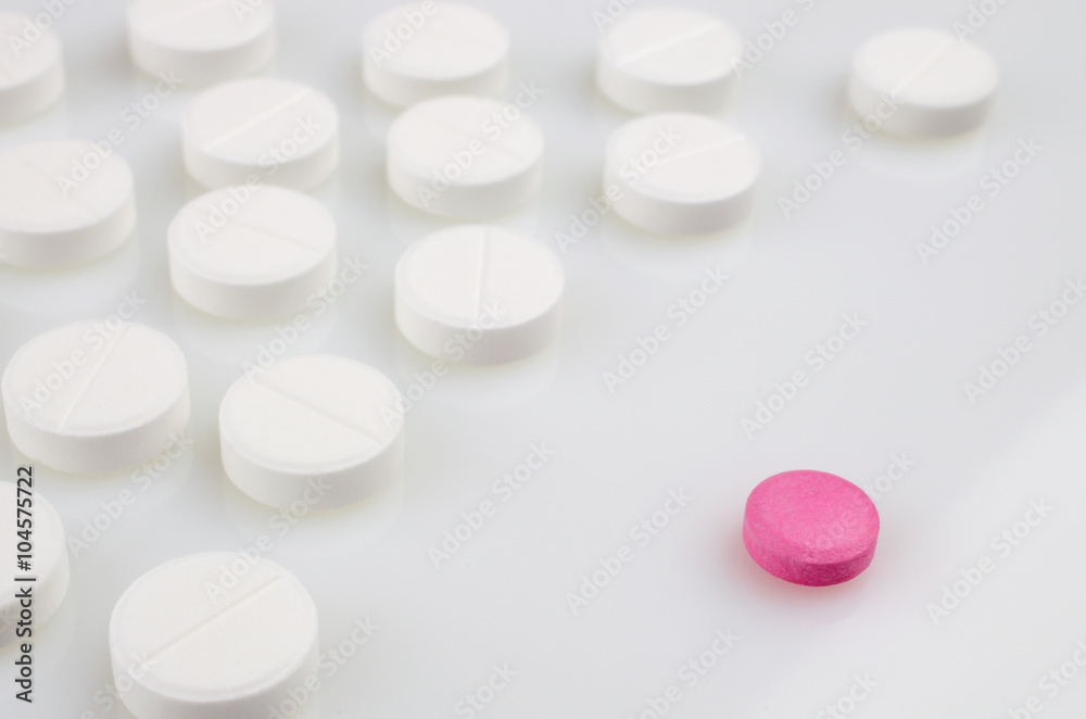 Pharmacy theme. Pink pill standing in front of the set of white pills Pharmacy theme. Pink pill standing in front of the set of white pills