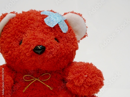 Photo of a red teddy bear with bandage over his head.