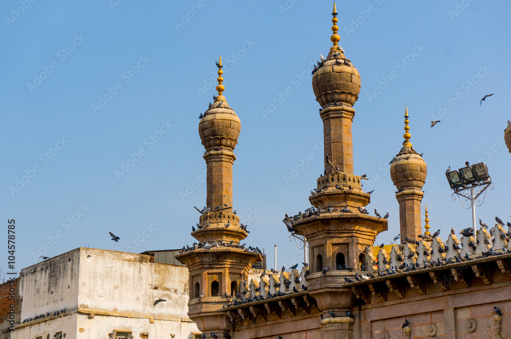 Thin minarets of a mosque with pigeons sitting