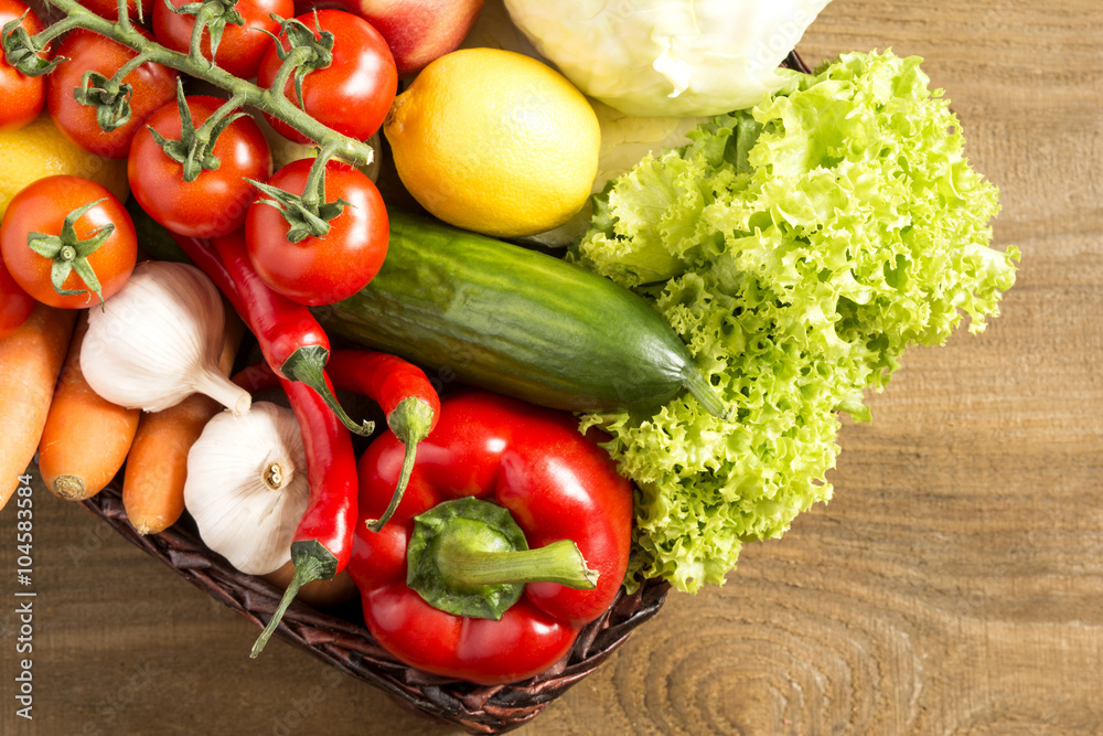 Wicker basket with fruits and vegetables on wooden table Wicker basket with fruits and vegetables on wooden table