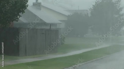 A torrential rainstorm falls in a suburban neighborhood.