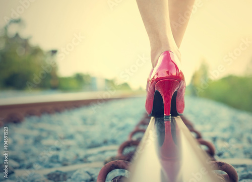 Female legs in red high heels on the rail of the railway. (Vinta