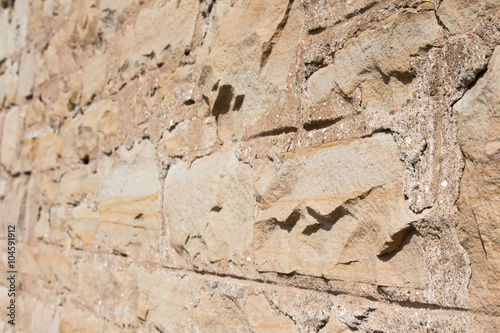 Selective focus on tan stone block wall
