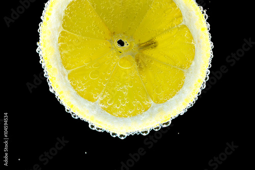 Slice of lemon in the gas water on the black