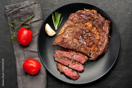 Medium rare grilled Steak Ribeye on dark background. Top view