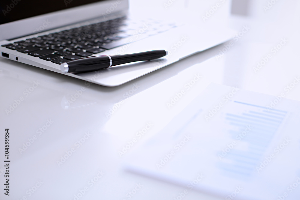 Office workplace with a laptop and financial documents on the light reflecting table Office workplace with a laptop and financial documents on the light reflecting table