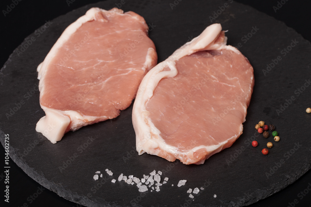 Fresh meat steaks on black slate background. Selective focus Fresh meat steaks on black slate background. Selective focus