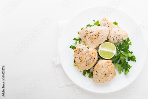 Chicken breasts with parsley and citrus on white background top view. Healthy food. Space for text.