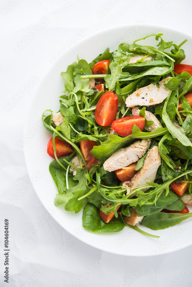 Fresh salad with chicken, tomato and greens (spinach, arugula) on white background top view. Healthy food. Fresh salad with chicken, tomato and greens (spinach, arugula) on white background top view. Healthy food.