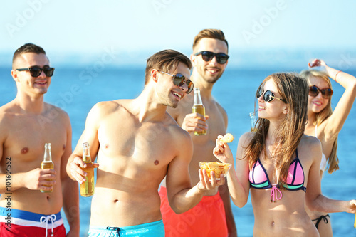 Happy young friends drinking beer at the beach  outdoors