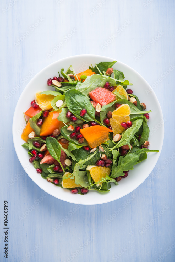 Fresh salad with fruits and greens on blue wooden background top view. Healthy food.