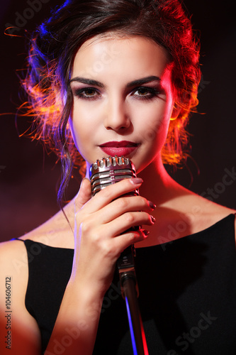 Young beautiful woman singing in colourful smoke, close up