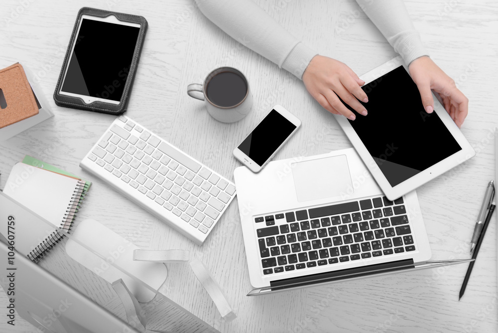 Concept of using electronics. Businesswoman works at office. Computer, laptop, tablet, cup of coffee and other things on the table. Top view Concept of using electronics. Businesswoman works at office. Computer, laptop, tablet, cup of coffee and other things on the table. Top view