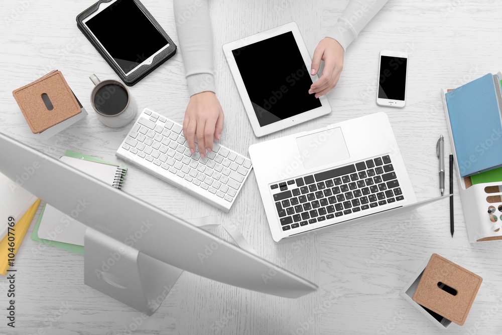 Concept of using electronics. Businesswoman works at office. Computer, laptop, tablet, cup of coffee and other things on the table. Top view Concept of using electronics. Businesswoman works at office. Computer, laptop, tablet, cup of coffee and other things on the table. Top view