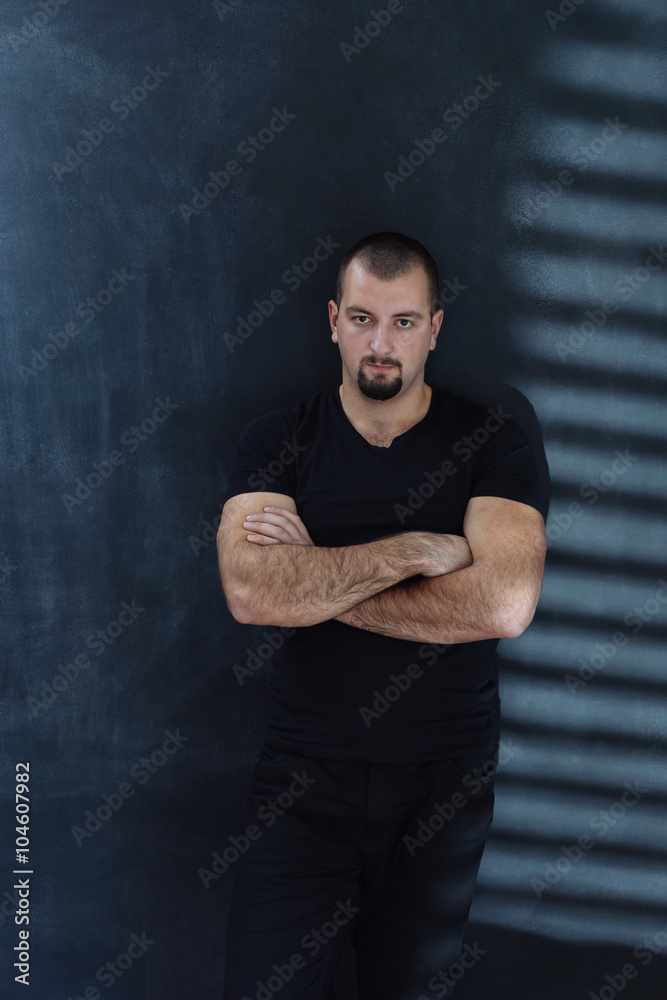 attractive man in shirt standing near the wall in the studio. li