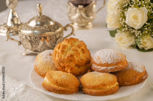 Shortbread cookies sprinkled with powdered sugar on a white plate is on the table, composition, flowers