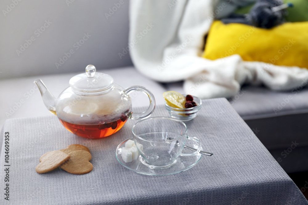 Tea cup and kettle on the table beside sofa