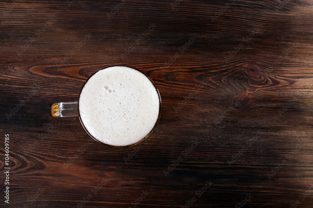 Glass of beer on wooden table, top view