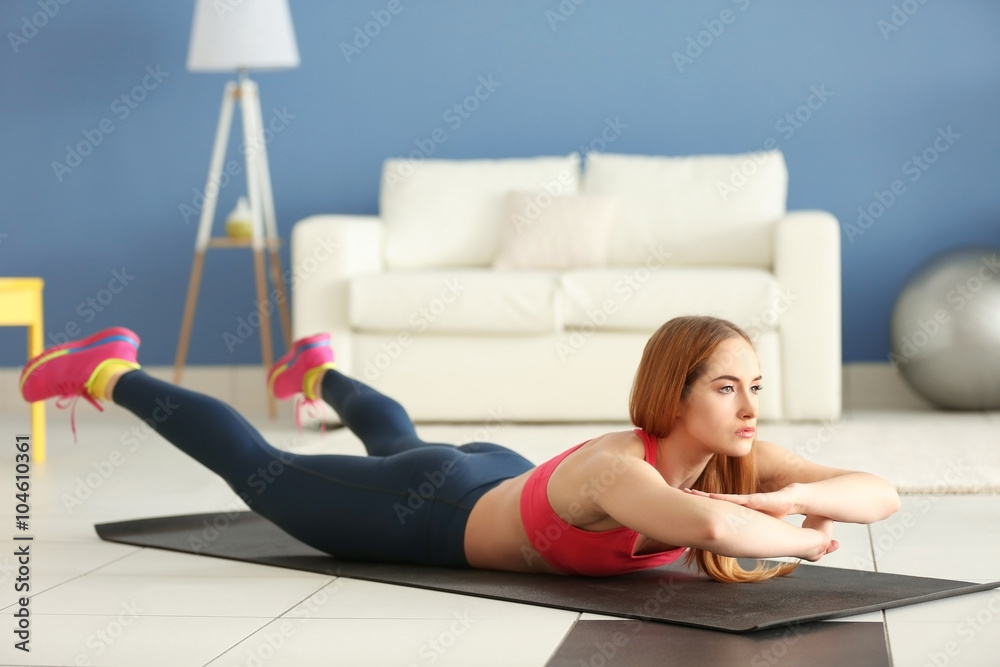 Young sportswoman doing exercises on a mat at home Young sportswoman doing exercises on a mat at home