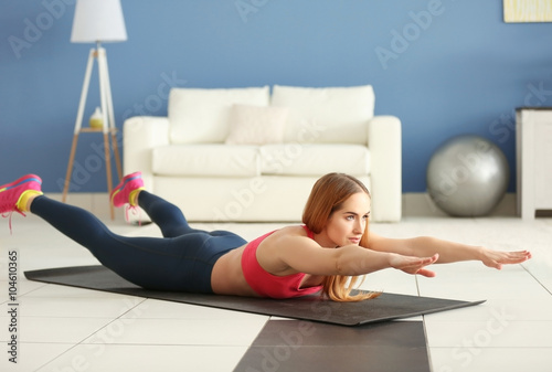 Young sportswoman doing exercises on a mat at home