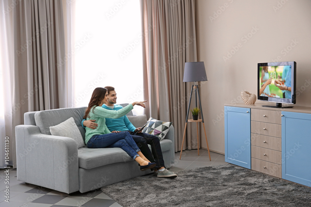 Young couple watching TV on a sofa at home Young couple watching TV on a sofa at home