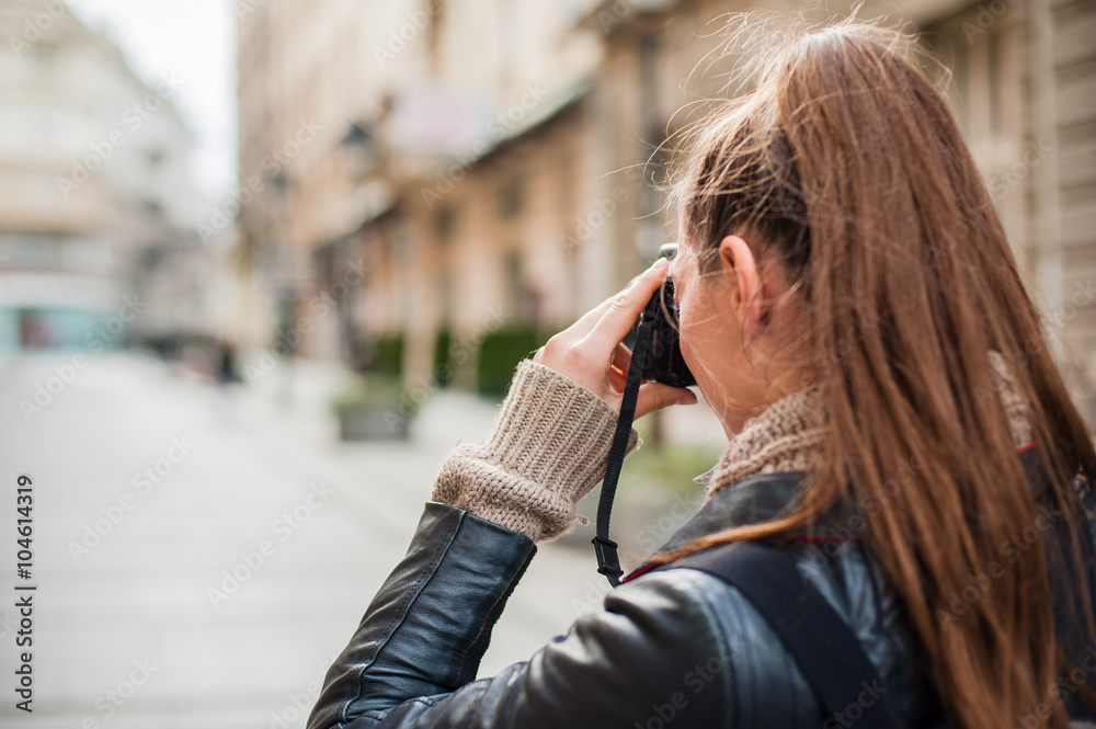 Fototapeta premium Young female photographer / Pretty young female tourist taking pictures in the city