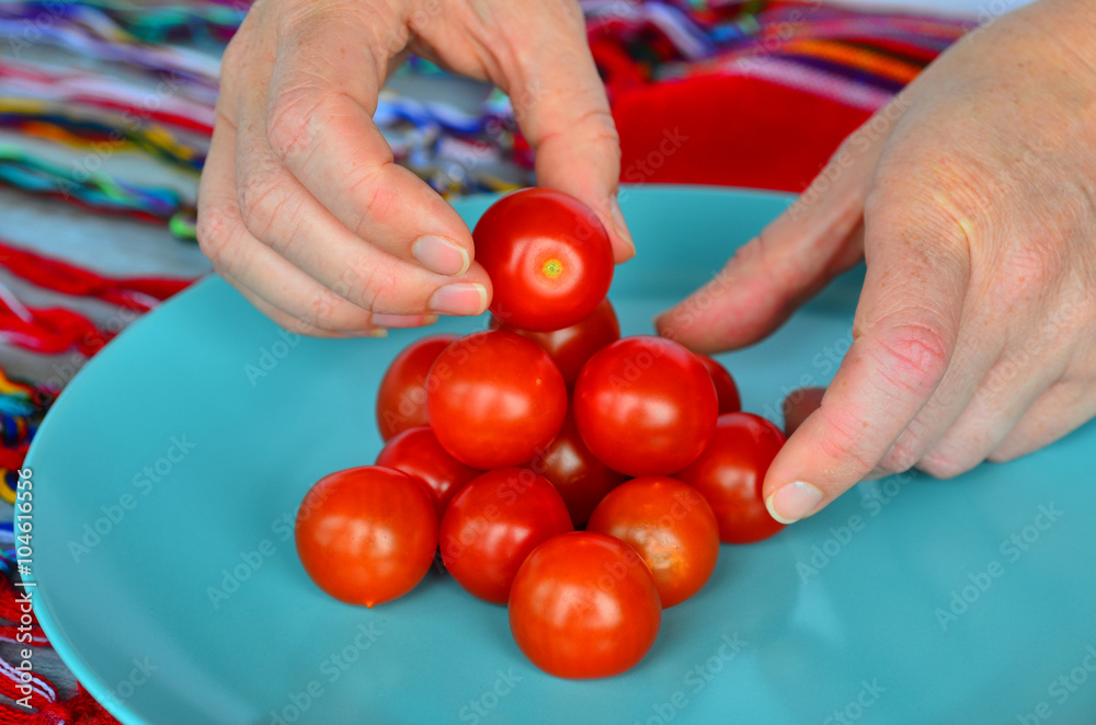 Woman hands arrange Cherry tomatoes in a plat Woman hands arrange Cherry tomatoes in a plat