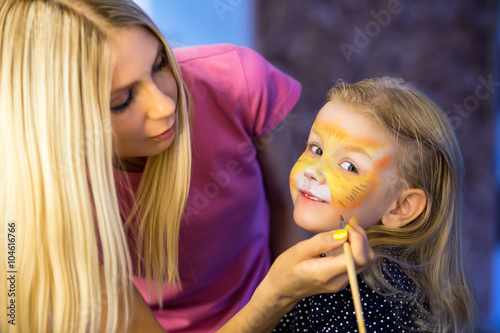 Woman painting the face of a little girl