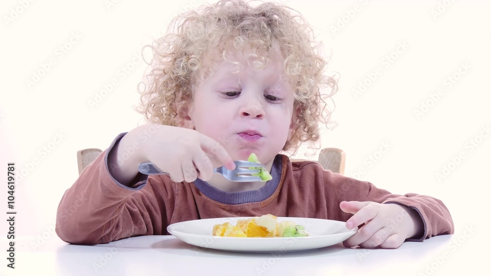 a small blond boy eating fruits with fork a small blond boy eating fruits with fork
